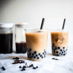 Black Milk Tea Boba: The Ultimate Guide to Making Perfect Bubble Tea at Home 5 Black Milk Tea Boba – A tall glass of creamy black milk tea with chewy tapioca pearls, served with a wide straw on a wooden table.