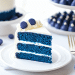 Blue Velvet Cake Recipe – The Rich & Elegant Dessert You Need to Try 5 Blue Velvet Cake Recipe – A slice of vibrant blue cake with cream cheese frosting on a white plate, garnished with blueberries.